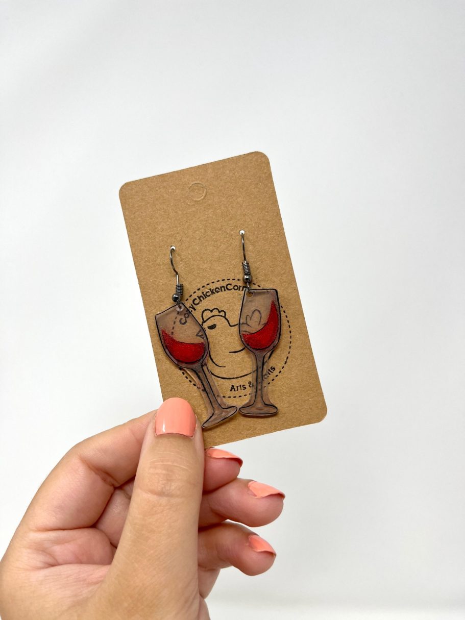 Eine Hand hält eine Karte mit Rotwein-Ohrringen daran.