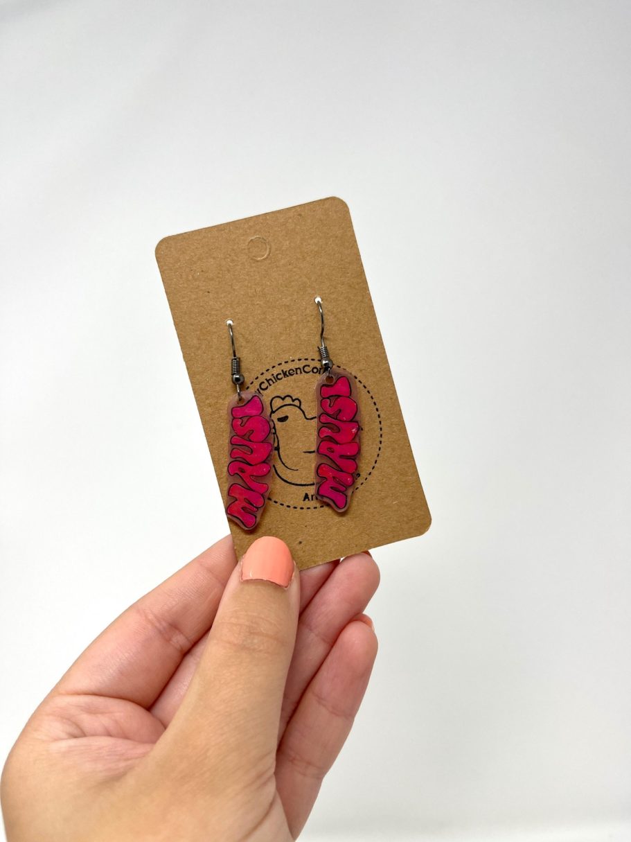 Eine Hand hält eine Karte mit Mausi-Ohrringen daran.