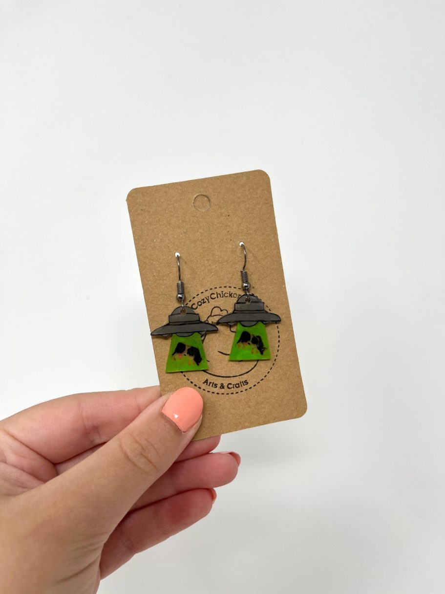 Eine Hand hält eine Karte mit Ufo-Ohrringen daran.